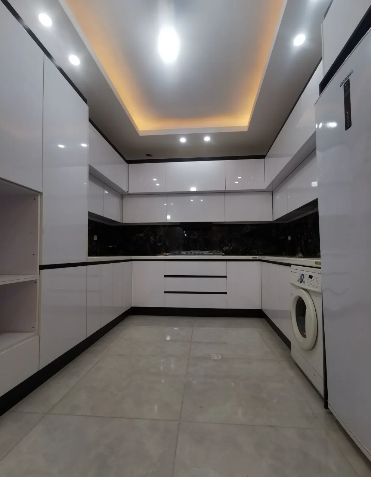 کابینت سفید هایگلاس با کف پوش سرامیکی سنگ بین کابینت مشکی نورپردازی از سقف
