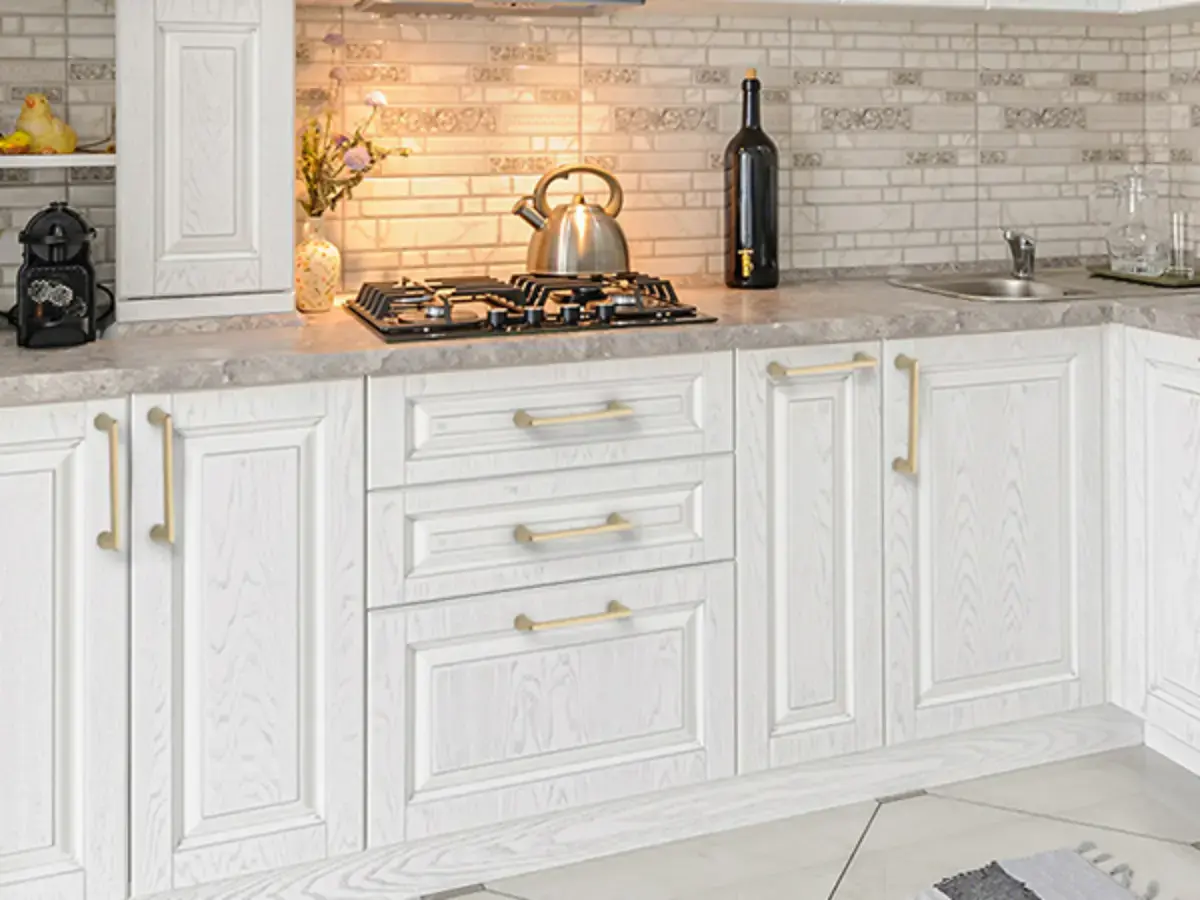 کابینت سفید ممبران سفید با دستگیره های طلایی استوانه ایی و دیوار آجری و صفحه طوسی