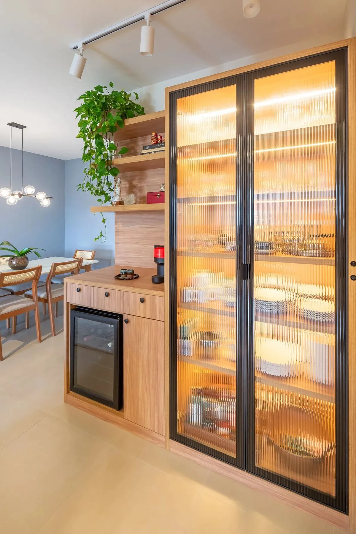 ویترین کابینت مدرن با شیشه مات طرح دار و قاب بندی مشکی و نورپردازی زرد و کابینت کافی بار متصل به آن