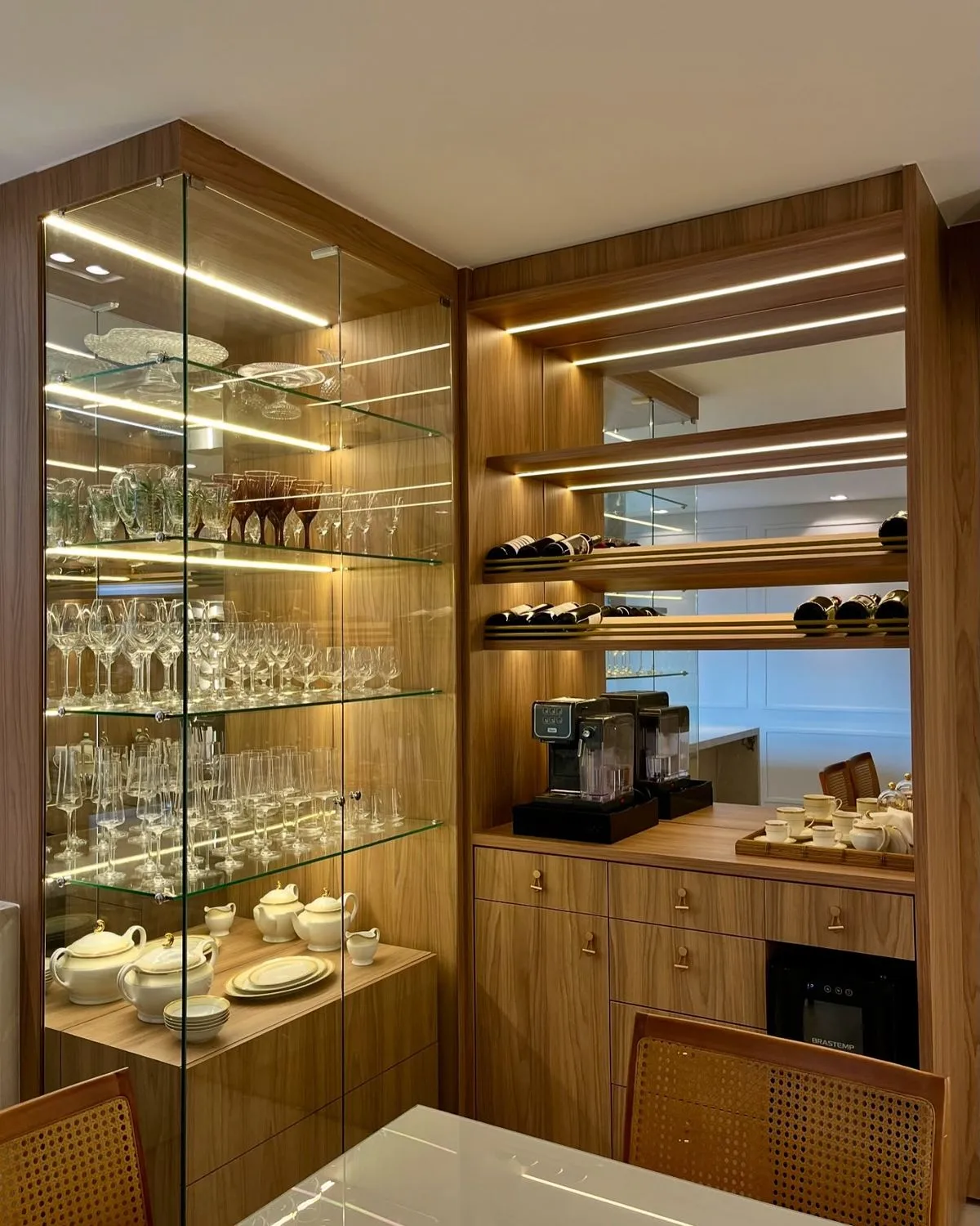 ویترین کابینت قهوهای با درب و قفسات شیشهای شفاف و نور پردازی خطی و کابینت کافی بار در ظلع مجاور ویترین